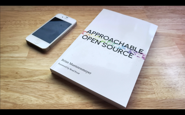 A picture of Approachable Open Source, next to a phone sitting on a desk.